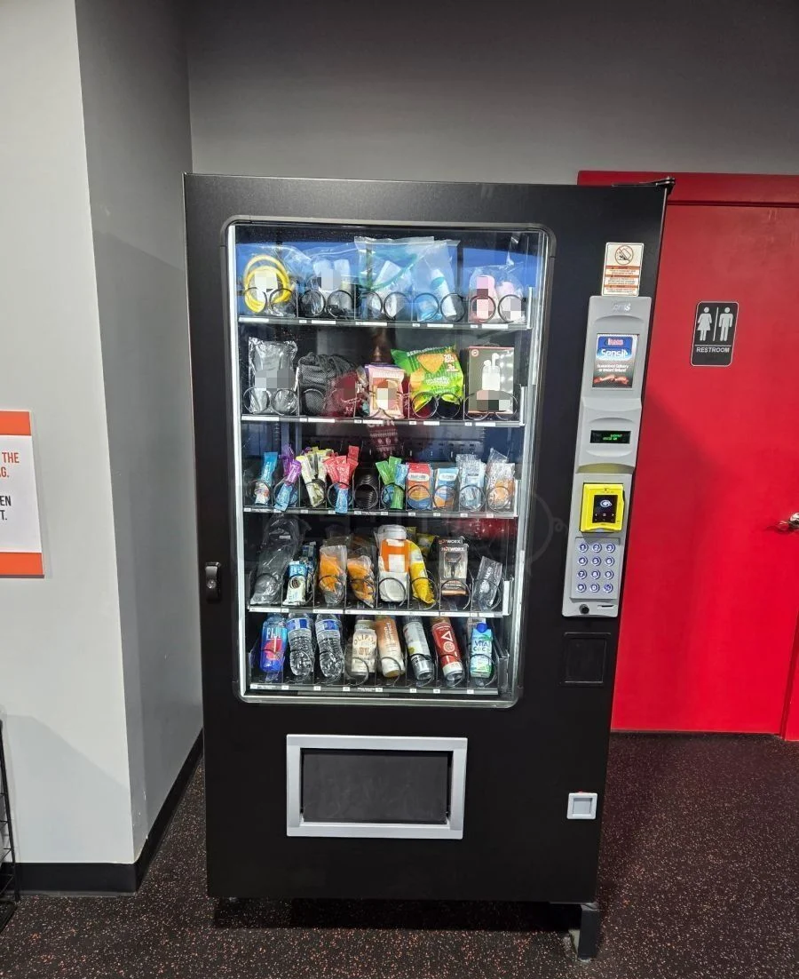 Free combination snack, drinks and gym-accessories vending machine installed inside a Sydney fitness studio next to the restrooms — protein bars, hydration, headphones and workout accessories in a single 24/7 unit